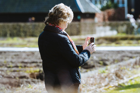 Woman photographing nature with smartphone.の写真素材