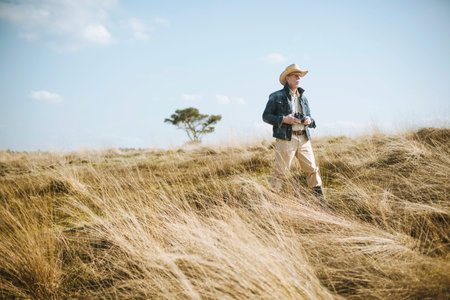 Man with hat and camera in field on safari.