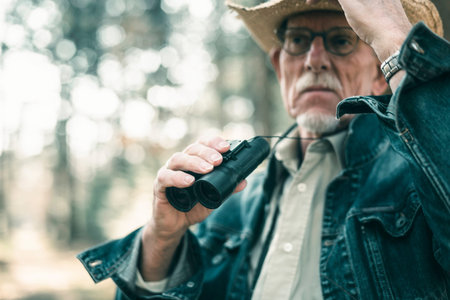 Man in forest holding binocular.の写真素材