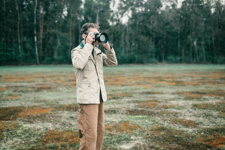 Nature photographer in meadow near forest taking pictures.の写真素材