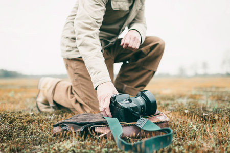 Nature photographer in field picking up camera.の写真素材