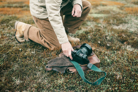 Nature photographer in field picking up camera.の写真素材