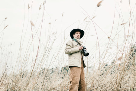 Nature photographer with hat standing between reed.の写真素材