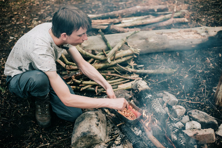 Wayfarer stirring meal in frying pan on campfire.の写真素材