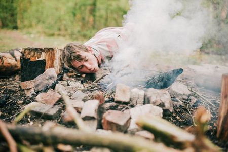 Camper blowing into campfire to get fire started.