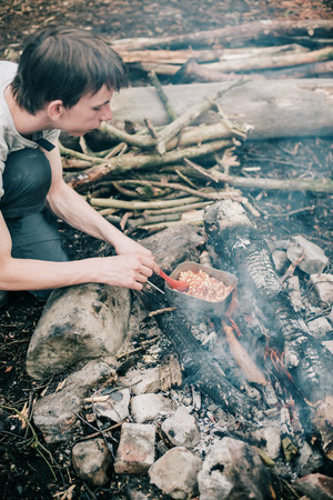 Wayfarer stirring meal in frying pan on campfire.の写真素材