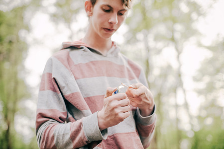 Teen man burning a wood chip at campsite.の写真素材