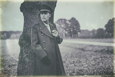 Antique black and white photo of resting 1940s military officer smoking cigarette under tree.の写真素材