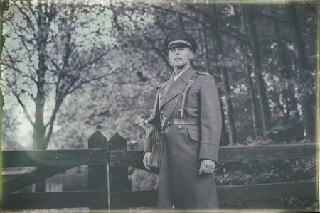 Antique black and white photo look of 1940s military officer standing at wooden fence in autumn...