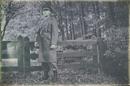 Antique black and white photo look of 1940s military officer standing at wooden fence in autumn...
