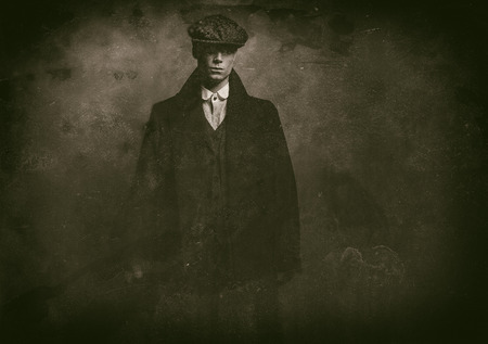 Antique wet plate photo of mysterious 1920s english gangster with flat cap and black coat.の写真素材