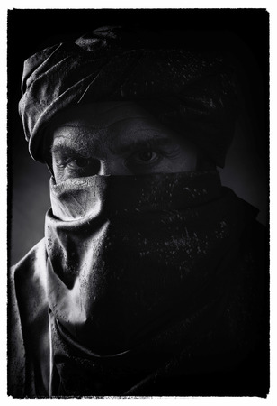 Vintage black and white photo of berber man in night light wearing turban with robe. Studio shot.の写真素材
