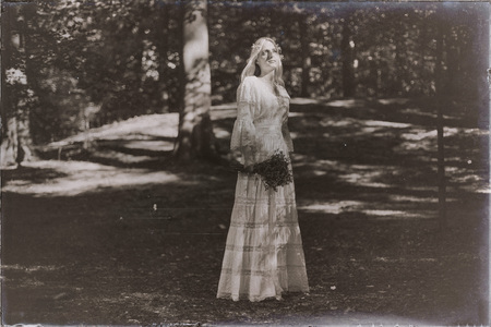 Vintage black and white photo of blonde bride catching sunlight in forestの写真素材