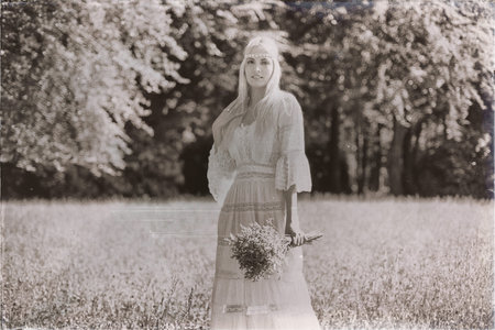 Vintage black and white photo of hippie bride with flower bouquet standing in meadowの写真素材