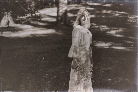 Vintage black and white photo of single bride in dappled sunlight of forest