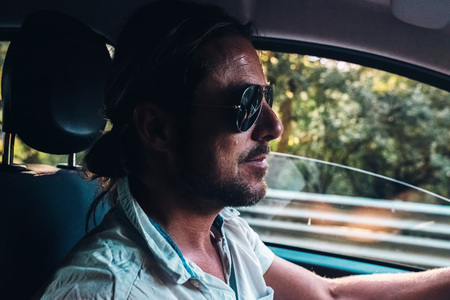 Interior shot of man with ponytail and sunglasses driving car.の写真素材