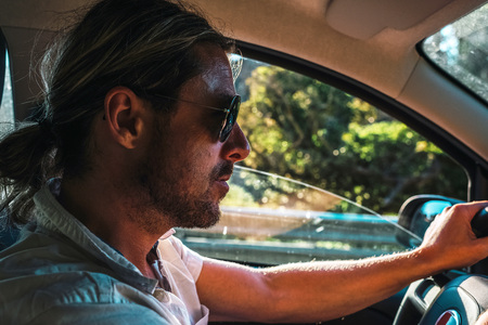 Interior shot of man with ponytail and sunglasses driving car.の写真素材