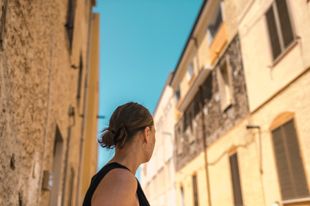 Rear view of brunette woman looking in street of old italian town. Sardinia. Italy.の写真素材