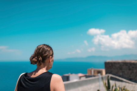 Brunette woman enjoying ocean view from roof top. Sardinia. Italy.の写真素材