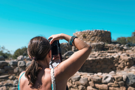 Female tourist photographing nuraghe site in summer. Arzachena. Sardinia. Italy.の写真素材