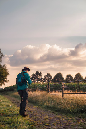 Man with backpack and hat on rural path.の写真素材