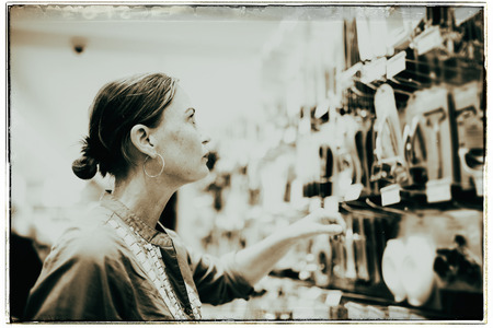 Vintage black and white photo of woman looking in kitchen tools in shopの写真素材