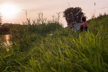 Trekking man sitting on chair at campsite in tall grass.の写真素材
