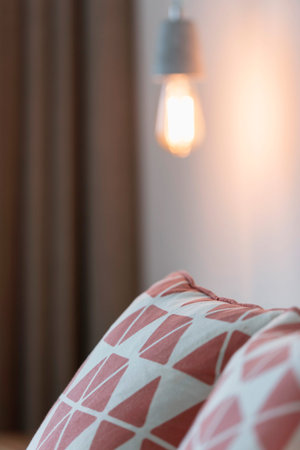 Pillows on bed with retro lightbulb hanging above.