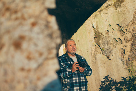 Photographer with gray hair and beard at old building. Old Perithia, Corfu, Greece.の写真素材