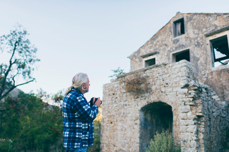 Tourist with gray hair and beard photographing architecture of Old Perithia, Corfu, Greece.の写真素材