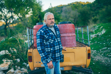 Middle aged man with grey hair and beard at trailer of vintage pick-up truck.の写真素材