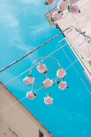 Wheels of bicycles with pink flowers hanging in streets of old town quarter of Alghero.の写真素材