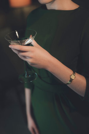 Retro girl in green dress standing with cocktail glass in room at night.の写真素材