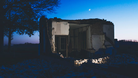 Part of demolished old house in countryside at dusk.