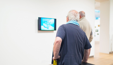 Visitors watching television in museum room. Rear view.の写真素材