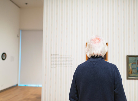 Senior man observing artwork in museum room. Rear view.の写真素材
