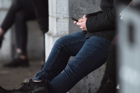 Traveler checking smartphone while waiting for train on platform.の写真素材