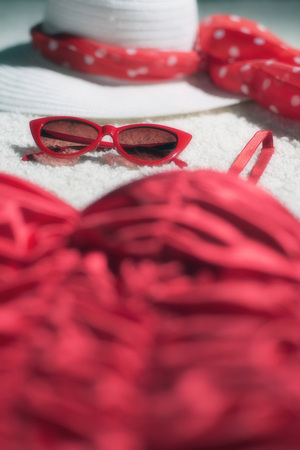 Vintage summer hat, red sunglasses and swimsuit displayed on white carpet floor.の写真素材