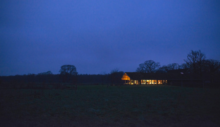 Countryside winter landscape with illuminated house at dusk.の写真素材