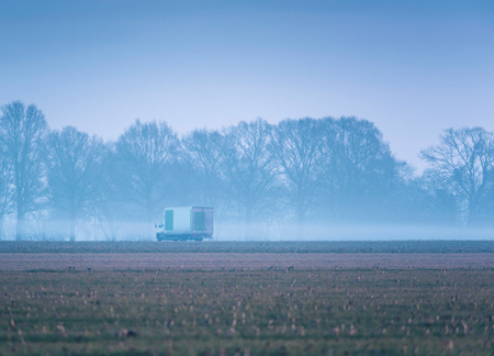 Small truck driving on misty country road in early morning.の写真素材