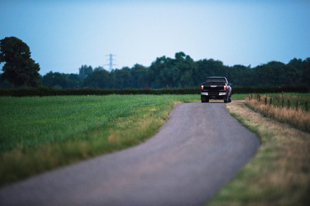Pickup truck driving on country road in evening.の写真素材
