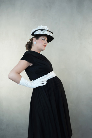 Vintage 1950s pregnant woman in black dress and hat.の写真素材
