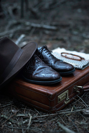 Abandoned briefcase with shoes, hat, glasses, watch and shawl in forest.の写真素材