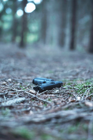 Lost black pistol in pine forest.