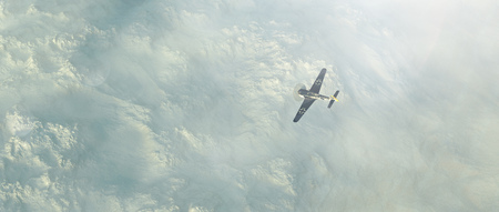World War 2 fighter plane over cloudy mountains. Aerial view.の写真素材