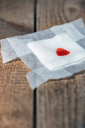 Used bandage with blood on wooden floor.の写真素材