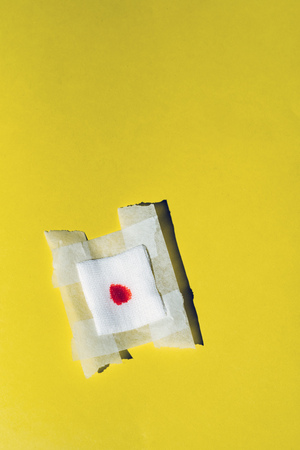 Bandage gauze with blood on yellow background. Top view.の写真素材