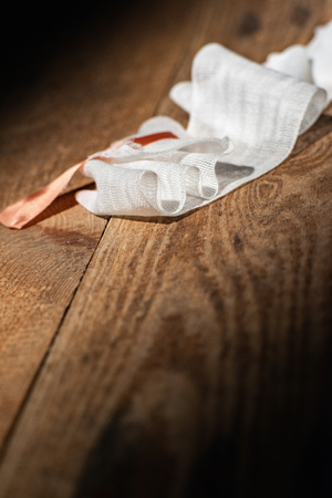 Used bandage with tape fallen on wooden floor.の写真素材