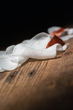 Used bandage with tape fallen on wooden floor.の写真素材