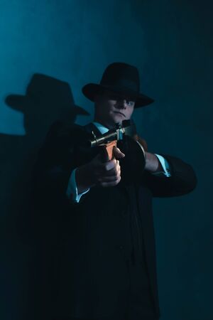 Retro gangster in hat shoots with machine gun.の写真素材